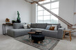 © otterspeer.com Stock - Rustic modern living room with a gray sectional sofa, patterned rug, and industrial-style accents.  Large window and exposed beams.