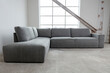 © otterspeer.com Stock - Gray sectional sofa in a modern, industrial-style room.  Concrete floor, large window.  Simple, clean design.