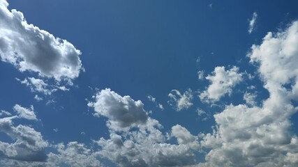 Wall Mural - timelapse of puffy white backlit clouds moving through a bright blue sky