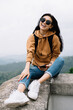© BullRun - Portrait of smiling asian female in sunglasses looking at camera sitting outdoors resting on vacations, positive woman traveler looking at camera laughing discover destination on wanderlust tour
