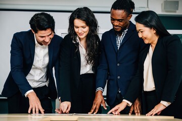 Wall Mural - Diverse colleagues stand at a conference room desk, actively participating in a successful meeting. Their teamwork, strategic planning, and cooperation drive business success.