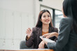 © Satori Studio - Two women in a business meeting, discussing ideas in a modern office environment, showcasing professional interaction and teamwork.