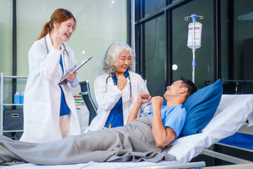 Wall Mural - Two female doctors examine a patient lying on a hospital bed,discuss the medical chart,administer medicine,and provide encouragement, ensuring compassionate care and fostering the patient's recovery