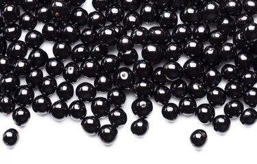 Poster - A pile of shiny black beads scattered on a white surface.