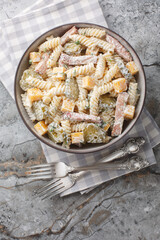 Wall Mural - Fusilli pasta salad with pickles, cheddar cheese, dill and bacon dressed with cream sauce close-up in bowl on table. Vertical top view from above