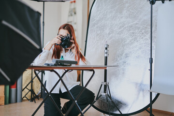 Female photographer taking photo of objects on background in photo studio with professional equipment