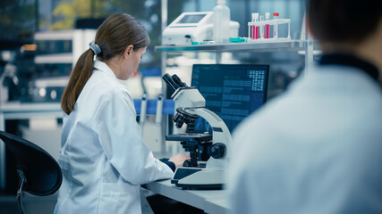 Aufkleber - Medical Research Scientist Looking at Biological Samples Under a Microscope in an Applied Science Laboratory. Portrait of a Caucasian Lab Engineer in White Coat Sitting with Turned Back to Camera