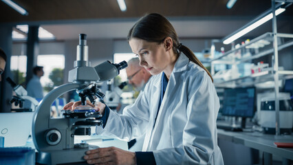 Aufkleber - Female Bioengineer Looking at DNA Samples Under a Microscope in a Modern Applied Science Laboratory. Portrait of a Young Lab Engineer in White Coat Working with Colleagues