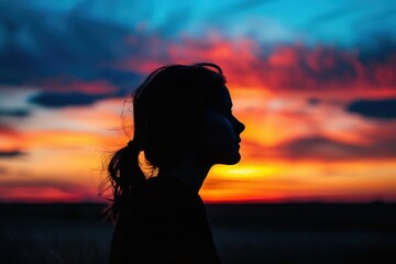 Poster - Sunset silhouette of a person standing on a hill with vibrant colors in the sky during twilight