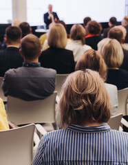 Female audience at the symposyum meeting, participants attendees in conference room hall listens to lecturer, group of women on a congress together listen to speaker on a stage at master-class