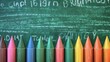 © ProPhotos - A row of multi-colored crayons in front of a board with inscriptions.