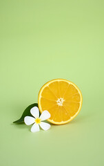 Aufkleber - A delicate orange slice rests beside a small white flower petal against a soft green background in the still life composition._00001_