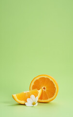 Aufkleber - A delicate orange slice rests beside a small white flower petal against a soft green background in the still life composition._00002_