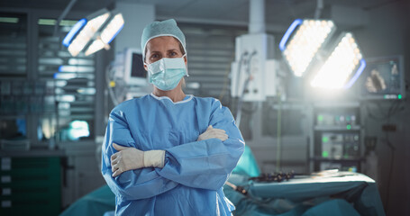 Poster - Portrait of a Middle Aged Female Doctor or Surgeon Wearing a Protective Face Mask, Disposable Surgical Cap and Overalls. Medical Person Calmly Looking at Camera in Operating Room