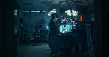 Poster - Diverse Surgical Team Working in a Darkened Operating Room Surrounded by Advanced Medical Equipment. Female Doctor Using a Scalpel and a Laparoscope while Performing a Complex Surgery