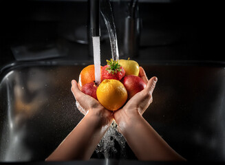 Wall Mural - Two hands gently cradle assorted fresh fruits under running tap water in a stainless steel sink.  Cleanliness, freshness, and healthy eating are emphasized.