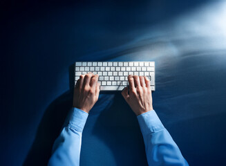 Aufkleber - Overhead view of hands typing on a white keyboard against a dark blue background.  Light streaks suggest speed and data flow.  A sense of late-night work or digital urgency is conveyed.