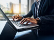 © YiuCheung - Close-up of hands typing on a laptop keyboard, showcasing efficient work and modern business practices.  The professional is dressed in a business suit.