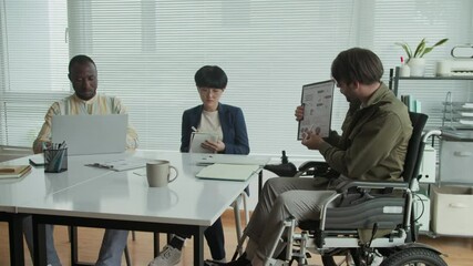 Wall Mural - Pan shot of Caucasian businessman with disability meeting with diverse coworkers at office for financial perspectives discussion