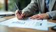 © stockphoto02 - A businesswoman analyzes financial data  using a pen to mark key points on graphs and charts.