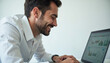 © stockphoto02 - A joyful man reviews positive business data on his laptop  smiling broadly.