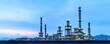 © Sasiwan - A panoramic view of a modern oil refinery with towering structures and a blue sky, showcasing industrial architecture and energy production.