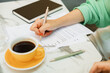 © RooM The Agency - Close-up of a woman sitting at an outdoor cafe signing documents and drinking coffee
