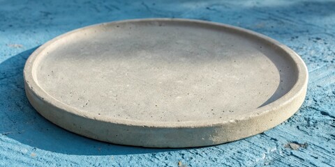 Aufkleber - A round concrete coaster with a rough textured surface sits on a blue painted wooden background.