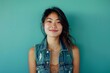© Markus Schröder - Portrait of a grinning asian woman in her 20s wearing a rugged jean vest isolated on soft teal background