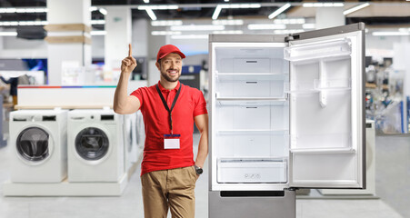 Wall Mural - Shop assistant leaning on a fridge and pointing