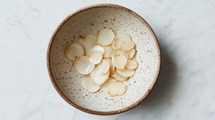 Aufkleber - Bowl of preserved garlic slices on a white background showcasing culinary textures and natural colors from an overhead perspective