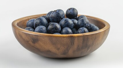 Aufkleber - Blueberries overflowing in a round wooden bowl set against a clean white background highlighting freshness and natural beauty