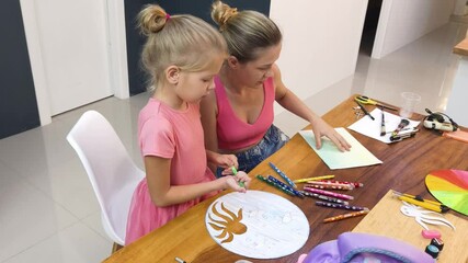 Wall Mural -  A mother and her young daughter engage in a colorful painting activity 