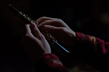 Poster - A person plays a flute, showcasing musical artistry in a dimly lit setting.