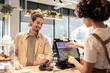 © ADDICTIVE STOCK - Friendly interaction between cafe cashier and customer at POS terminal