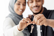 © Prostock-studio - Closeup of key chain in smiling muslim couple hands, selective focus. Happy middle-eastern family husband and wife showing key from their apartment, celebrating moving to new house
