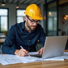 engineer in yellow helmet works on construction drawing. project manager uses laptop, papers. man pl