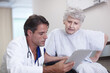 © peopleimages.com - Healthcare, tablet and senior woman with doctor, hospital and explaining of diagnosis and retirement. Clinic, medical professional and conversation with person with disability, wheelchair and talking