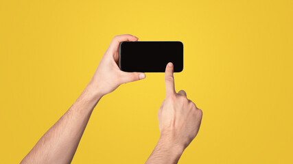 Poster - Unrecognizable millennial guy touching screen of cellphone over light background, space for mobile app design