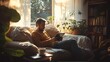 © aun - A man using a tablet while sitting on a cozy couch, surrounded by books and a cup of coffee, with natural light streaming through a window