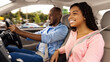 © Prostock-studio - Happy African American man and woman going on summer vacation by car. Beautiful millennial couple sitting inside their new auto, young family cheerfully smiling looking at road, profile side view