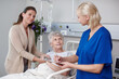 © peopleimages.com - Healthcare, woman and senior mother in hospital, smile and paperwork for discharge, nurse and retirement. Clinic, caregiver and happy for recovery, documents and help for elderly person with daughter