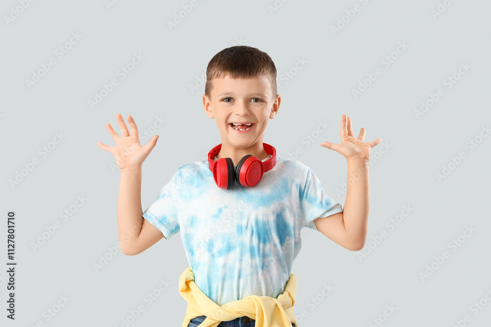 Happy little boy with headphones on light background