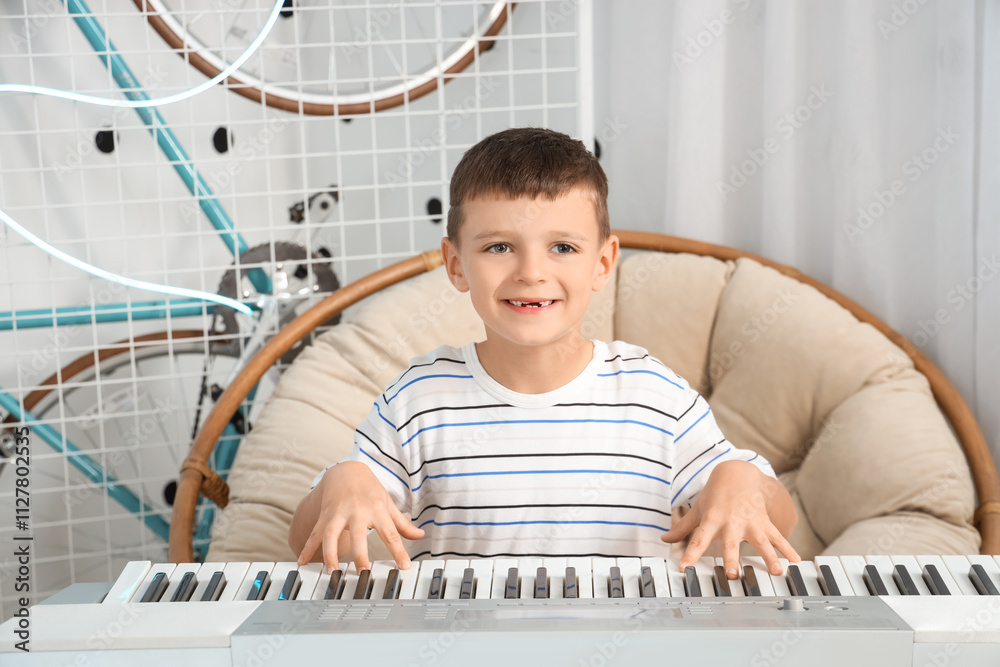 Cute little boy playing synthesizer in bedroom