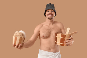 Wall Mural - Handsome man with sauna supplies on beige background