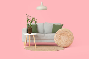 Canvas Print - Table with bamboo stems in vase, pouf, sofa and lamp on pink background