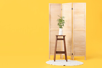 Canvas Print - Table with bamboo stems in vase, rug and folding screen on yellow background