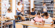 © JackF - Schoolchildren doing their homework in the school library write out a synopsis from the textbook in a exercise book