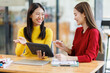 © David - Shot of two businessasianwomen working together on digital tablet. Creative female executives meeting in an office using tablet pc and smiling.