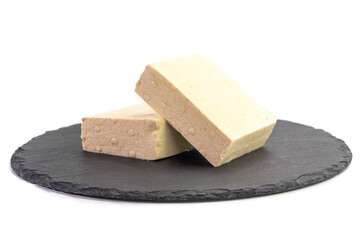 Two pieces of raw tofu on a gray plate isolated on white background.Vegan food ingredient in Asian cuisine, Plant based diet